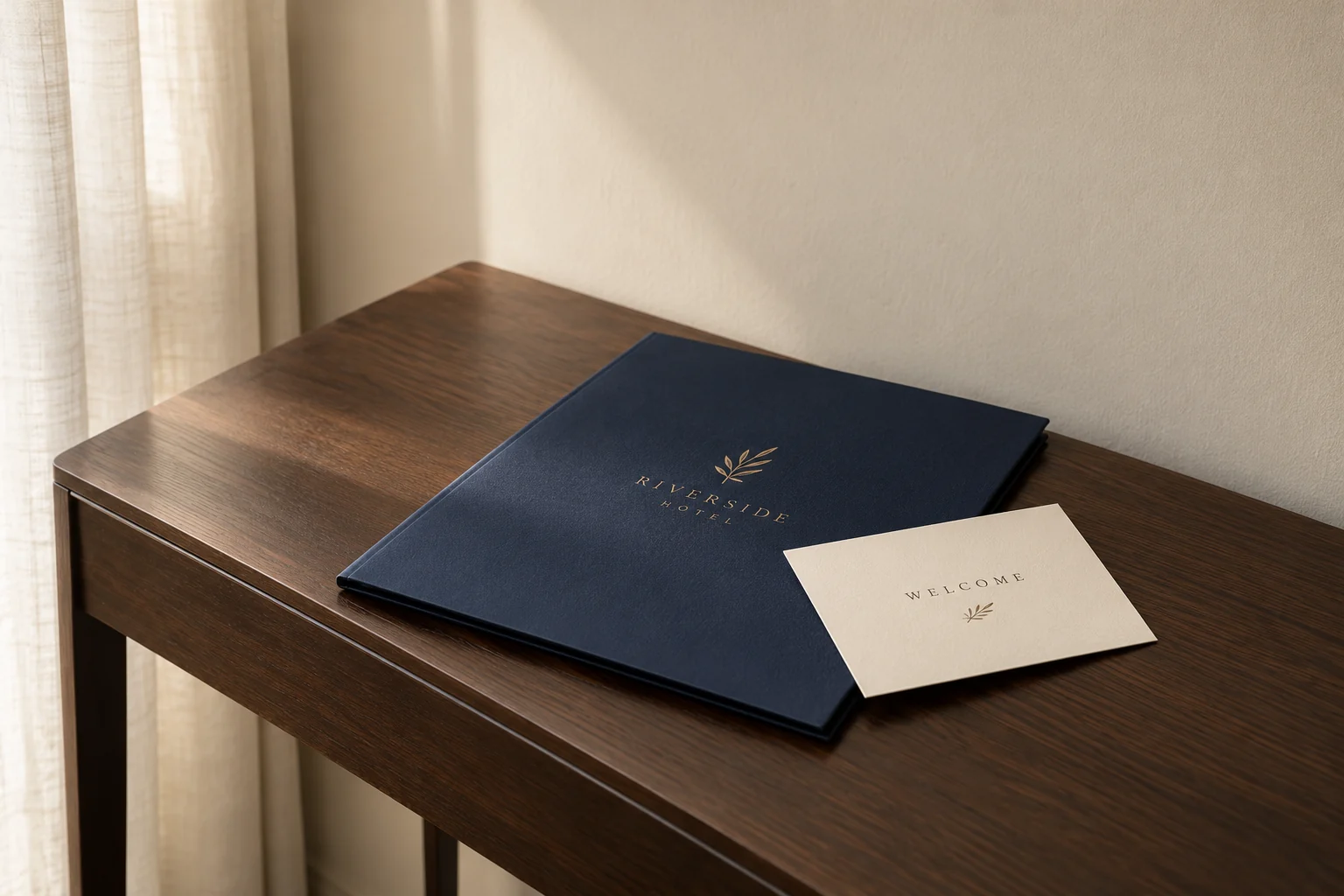 Illustrative mockup: a navy hotel welcome folder and ivory card on a sparse dark wood console