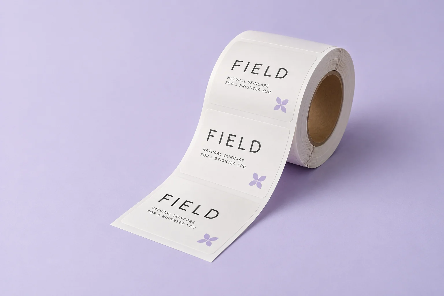 Illustrative mockup: a single roll of retail labels on a pale lavender studio surface